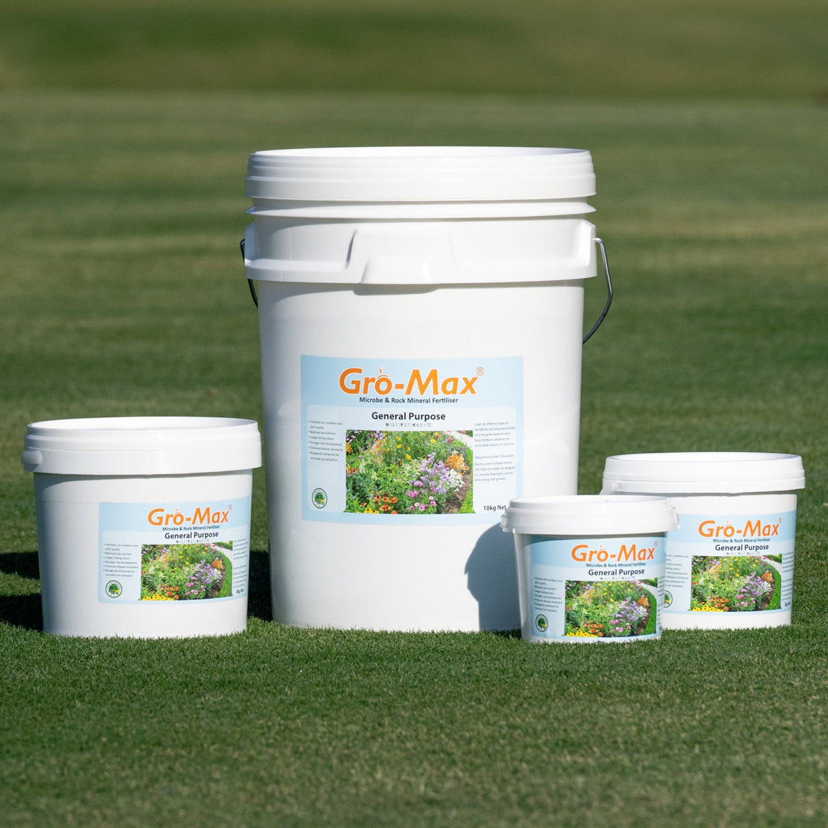 Four white Gro-Max General Purpose fertilizer buckets on green grass, varying in size.